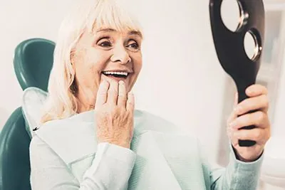woman loving her new smile while looking in the mirror