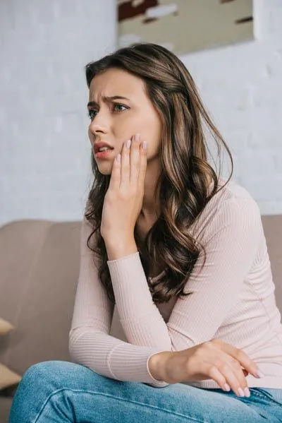 woman experiencing tooth pain holding her mouth